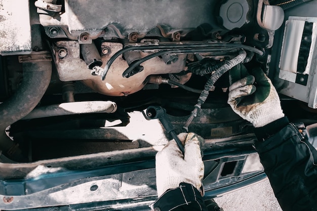 Reemplazo de cables de alta tensión en el motor del automóvil Hombre mecánico reparando un vehículo viejo está en servicio Abra el capó automático