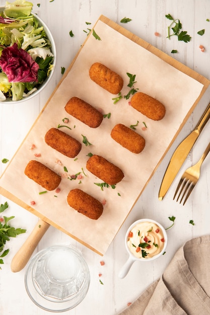 Foto refeição contendo croquetes com salada e maionese