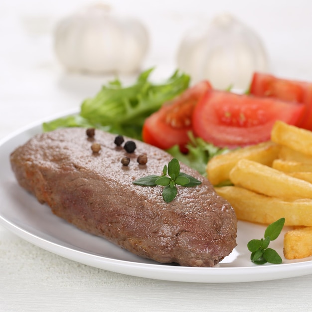 Refeição de carne de bife frito com batatas fritas legumes e alface no prato