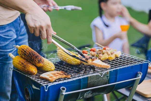 Refeição feliz em família ao ar livre festa no quintal churrasco grelhado carne assada e pão de milho cozinhando no fogão de churrasco closeup