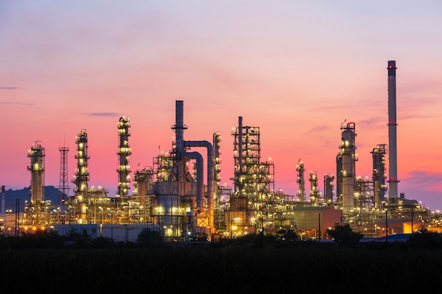 Refinaria de petróleo e planta e coluna de torre da indústria petroquímica em oleoduto industrial de petróleo e gás com céu vermelho de nuvens no fundo da manhã.