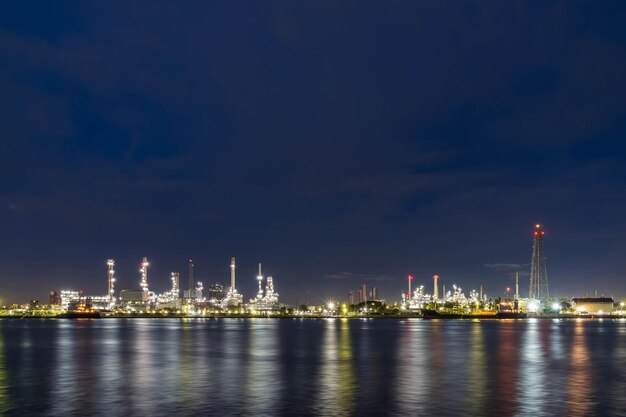 Foto refinería de petróleo por la noche industria petroquímica y energética con refección en el río