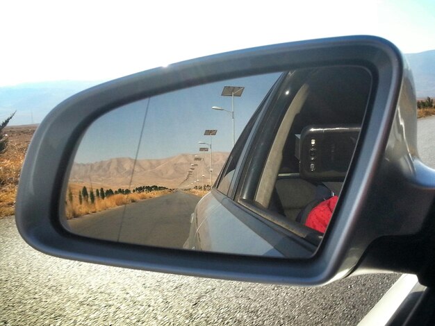 Foto reflejo de la carretera y las montañas en el espejo lateral