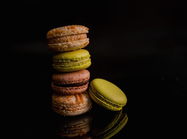 Foto reflejo de delicias macarrones marrones y verdes sobre fondo de espejo oscuro