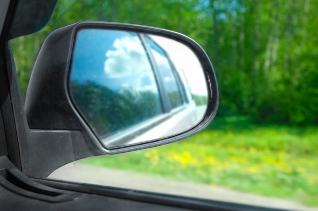 Reflejo del espejo retrovisor lateral del automóvil en movimiento en la carretera Carretera a lo largo del bosque verde y árboles en verano Concepto de viaje de viaje y turismo Hermosa naturaleza y paisaje Carretera a toda velocidad