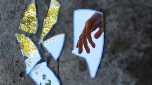 Foto el reflejo de una mano humana en un espejo roto