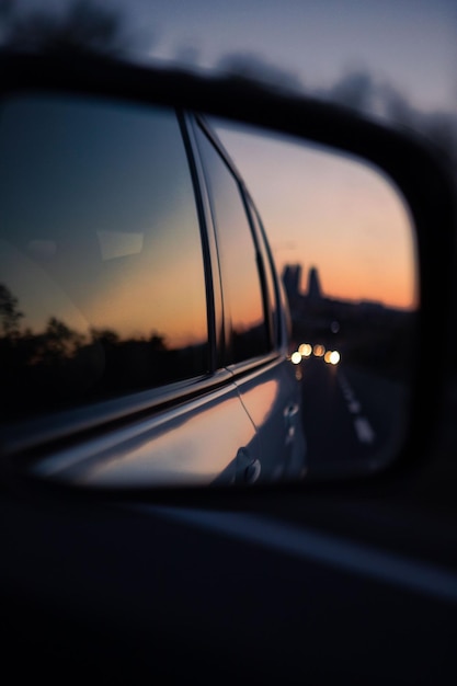 Reflejo en la puesta de sol del espejo retrovisor del coche en el espacio de la copia de la carretera