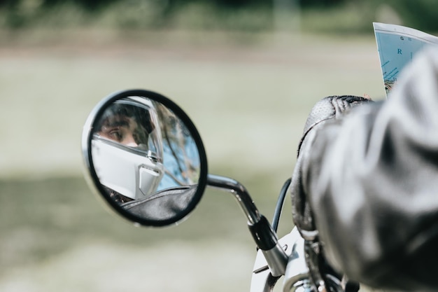 Reflejo de un retrovisor de un hombre en moto con un casco con espacio de copia. Sobre el tema de la ruta. Viaja con seguridad y usando protección mientras conduces.