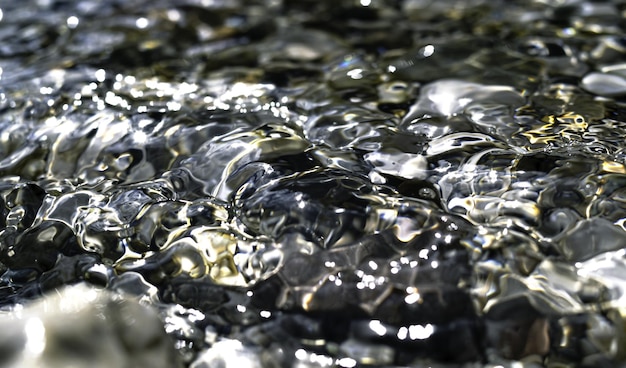 Reflejos plateados y dorados en la superficie del agua Imagen de fondo perfecta Piedras en el fondo