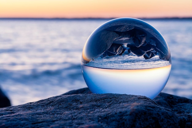 Reflexão da praia e do mar em uma bola de cristal durante o pôr do sol