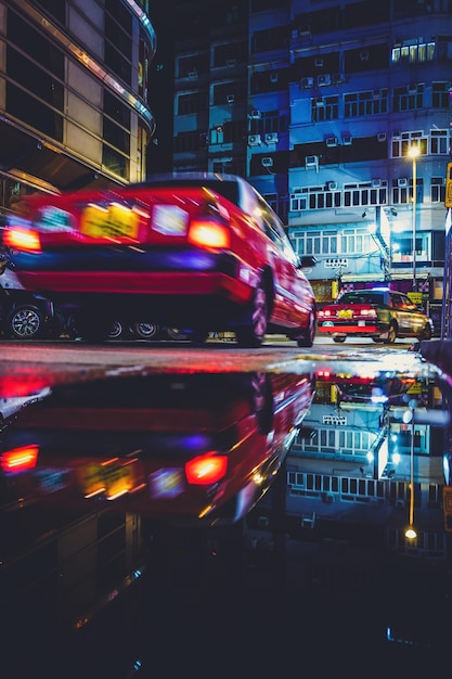 Reflexão de carros e edifícios na poça na rua à noite