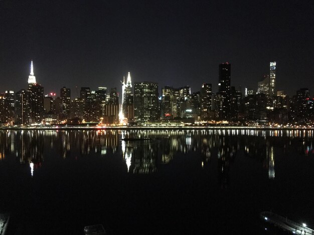 Foto reflexão de edifícios iluminados na água à noite