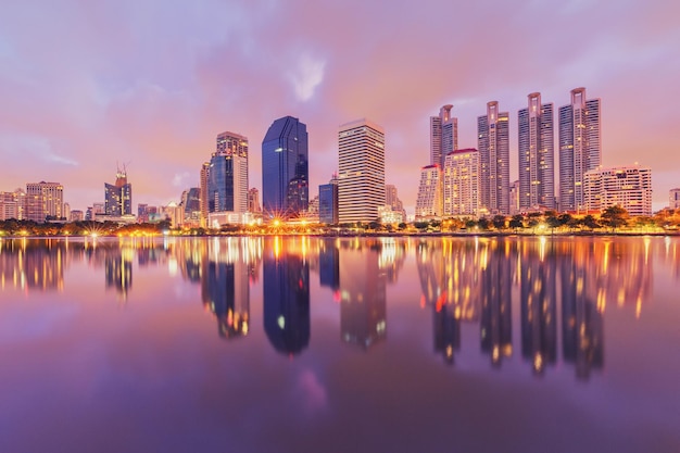 Reflexão de edifícios iluminados no rio contra o céu durante o anoitecer