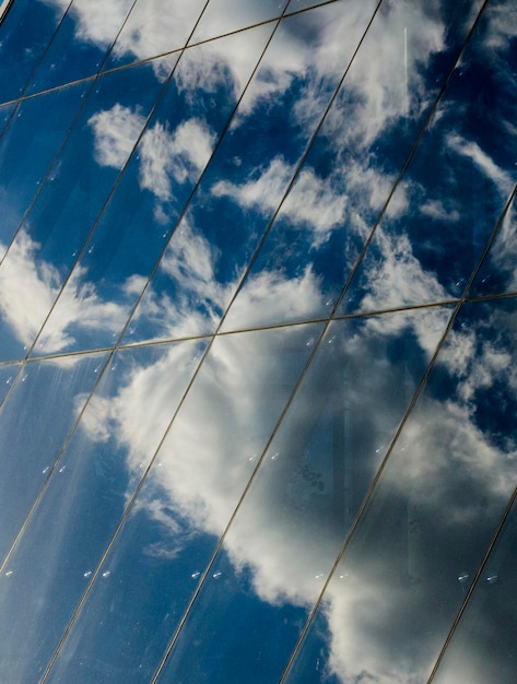 Reflexão de nuvens e céu azul na parede de vidro de um centro de negócios moderno fundo de foto