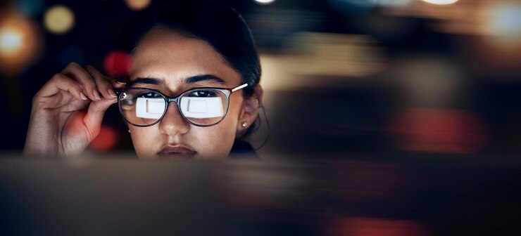 Foto reflexão de óculos de mulher e computador à noite para planejamento de pesquisa e tecnologia no site rosto de mulher trabalhando até tarde no escritório escuro da área de trabalho e lendo visão de foco de rede on-line e internet