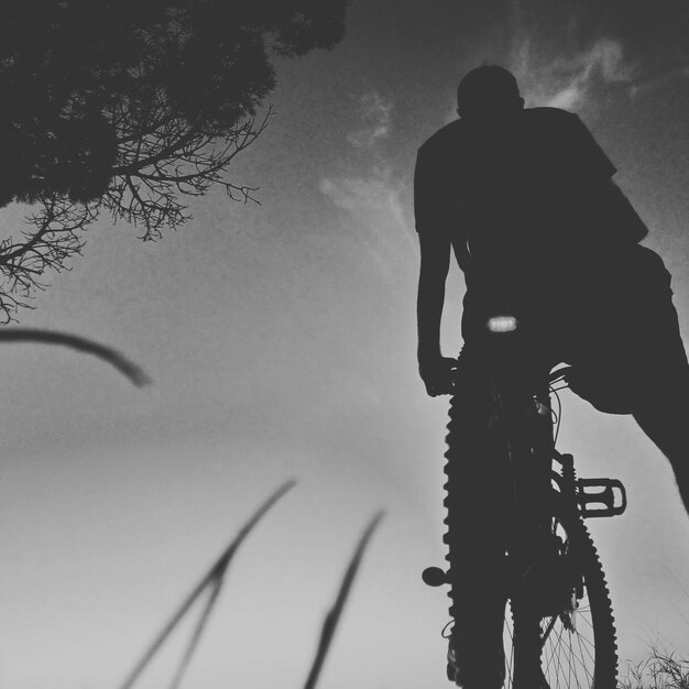 Foto reflexão de um homem com uma bicicleta contra o céu