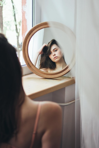 Reflexão de uma bela mulher no espelho em casa