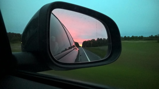 Reflexão do automóvel na estrada no espelho lateral