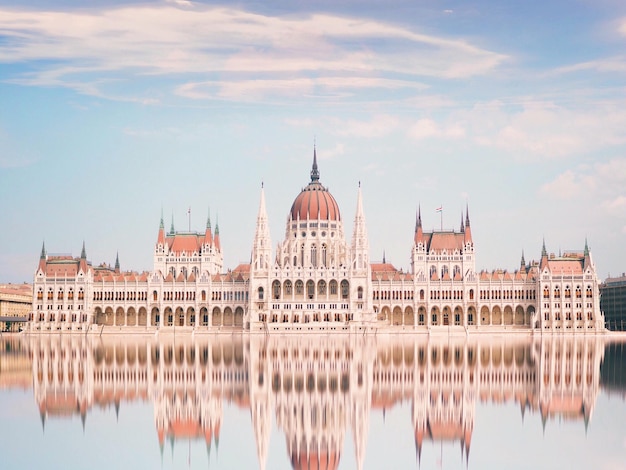 Reflexão do edifício do parlamento húngaro no rio contra o céu