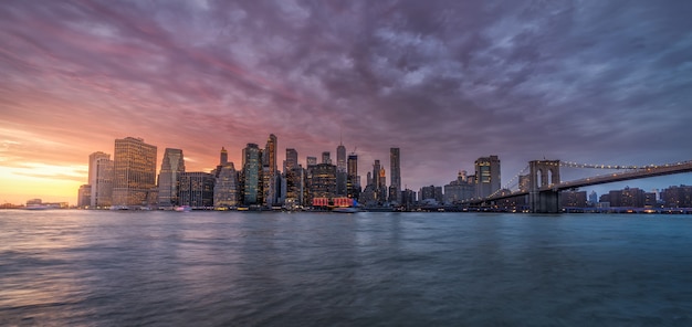 Reflexão do horizonte de nova york no rio hudson na ponte de brooklyn ao pôr do sol