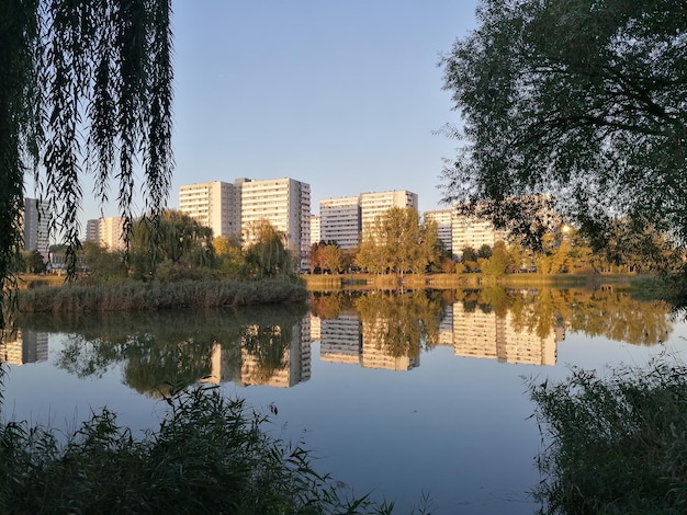 Reflexión de árboles y edificios en el lago contra el cielo