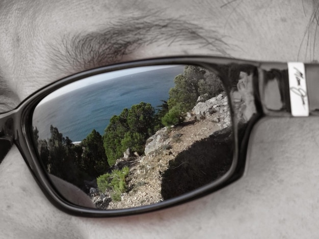 Reflexión de los árboles y el mar azul en gafas de sol