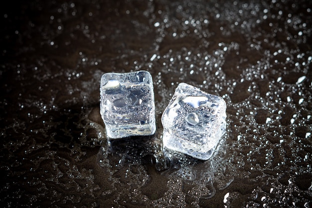 Reflexión de los cubitos de hielo en el fondo negro de la tabla.