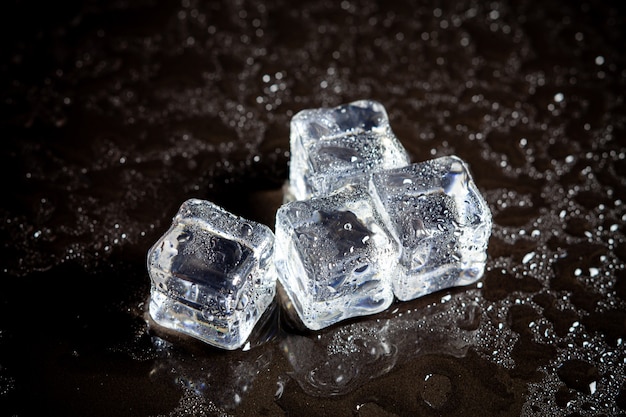 Reflexión de los cubitos de hielo en el fondo negro de la tabla.