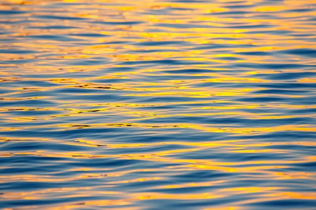 Reflexion der untergehenden Sonne in einer Wasserwelle. Natürliche Hintergrundtextur