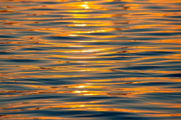 Reflexion der untergehenden Sonne in einer Wasserwelle. Natürliche Hintergrundtextur