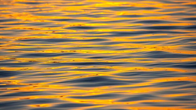 Reflexion der untergehenden Sonne in einer Wasserwelle. Natürliche Hintergrundtextur