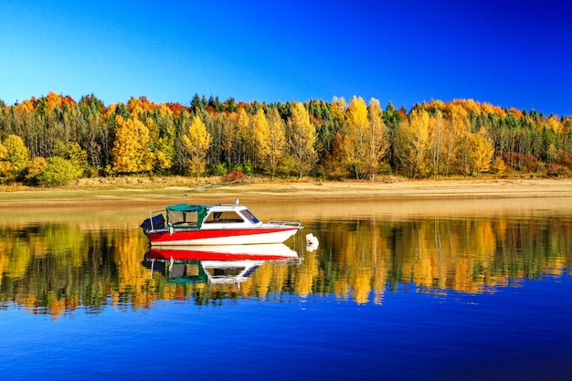 Reflexion des Bootes und der bunten Herbstbäume auf der Wasseroberfläche