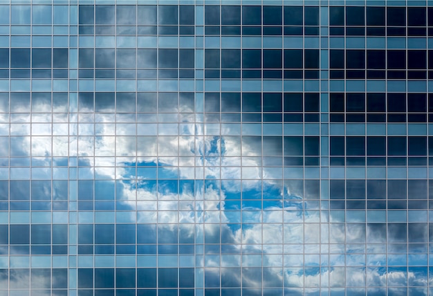 Reflexion des Himmels und der Wolken in den Fenstern eines mehrstöckigen Glasgebäudes.