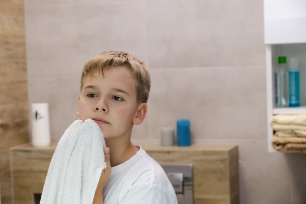 Reflexion eines Schuljungen, der sich nach dem Waschen im Badezimmer das Gesicht mit einem Handtuch abwischt