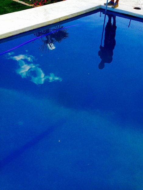 Foto reflexión de un hombre de pie en el borde de la piscina