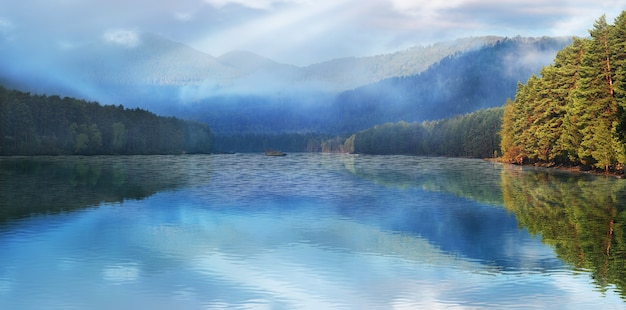 Reflexion im See von Berggipfeln im Nebel