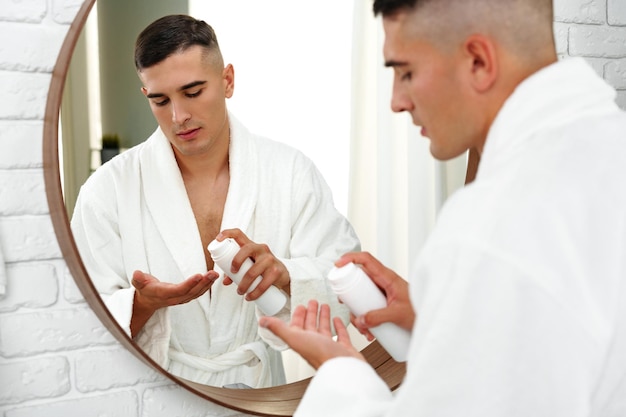 Reflexión de un joven afeitándose en el espejo del baño de cerca