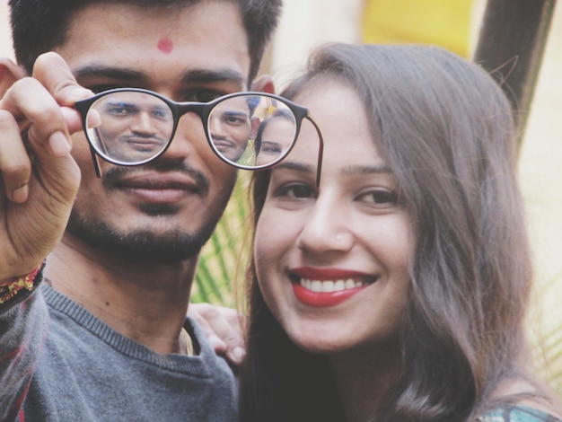 Reflexión de una joven pareja sonriente con gafas.