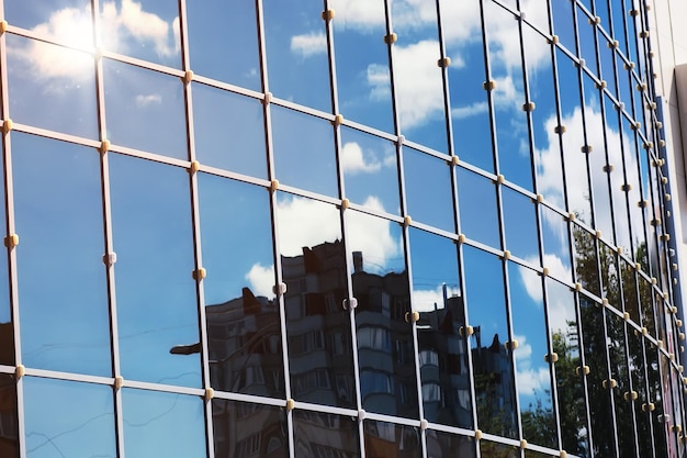 Reflexión de la nube del cielo de la luz del sol en el edificio de oficinas de cristal