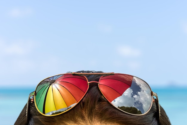 Foto reflexión del paraguas cayendo sobre las gafas de sol en la cabeza de la mujer