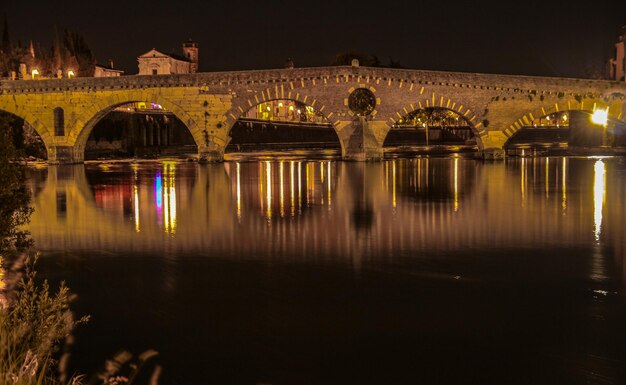 Reflexión de un puente iluminado en el agua por la noche