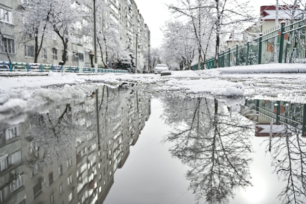 Reflexión sobre el charco del paisaje nevado de la ciudad del invierno.