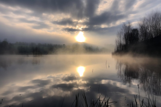 Reflexión del sol en el lago con nubes de niebla en el fondo creada con AI generativa