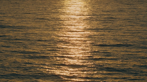 Reflexión del sol y ondulaciones en la superficie del agua de mar al atardecer con fondo de agua de mar