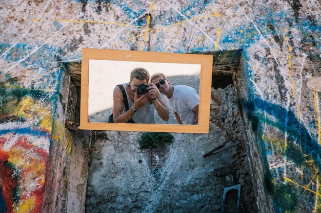 Reflexion von Menschen, die durch die Kamera im Spiegel an der Wand fotografieren
