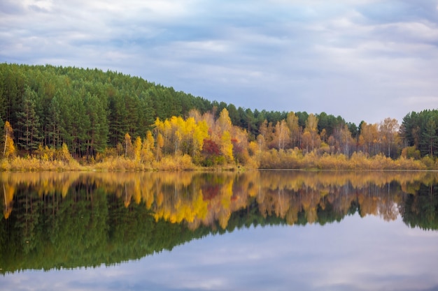 Reflexiones de árboles de follaje colorido en el agua tranquila del estanque en un hermoso día de otoño. Un lugar tranquilo y hermoso para relajarse.