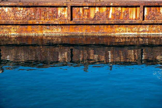 Reflexiones del muelle del puerto industrial viejo del metal oxidado en el agua