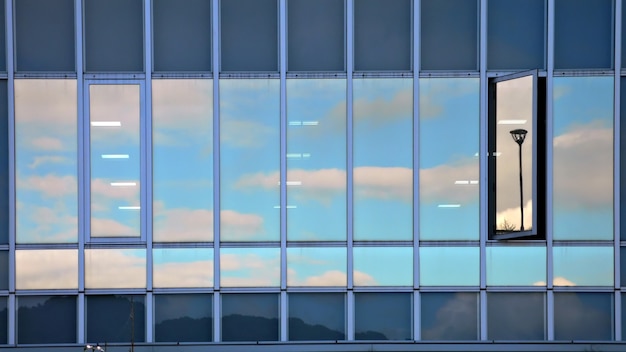 Reflexo de céu nublado na parede de vidro de um edifício moderno