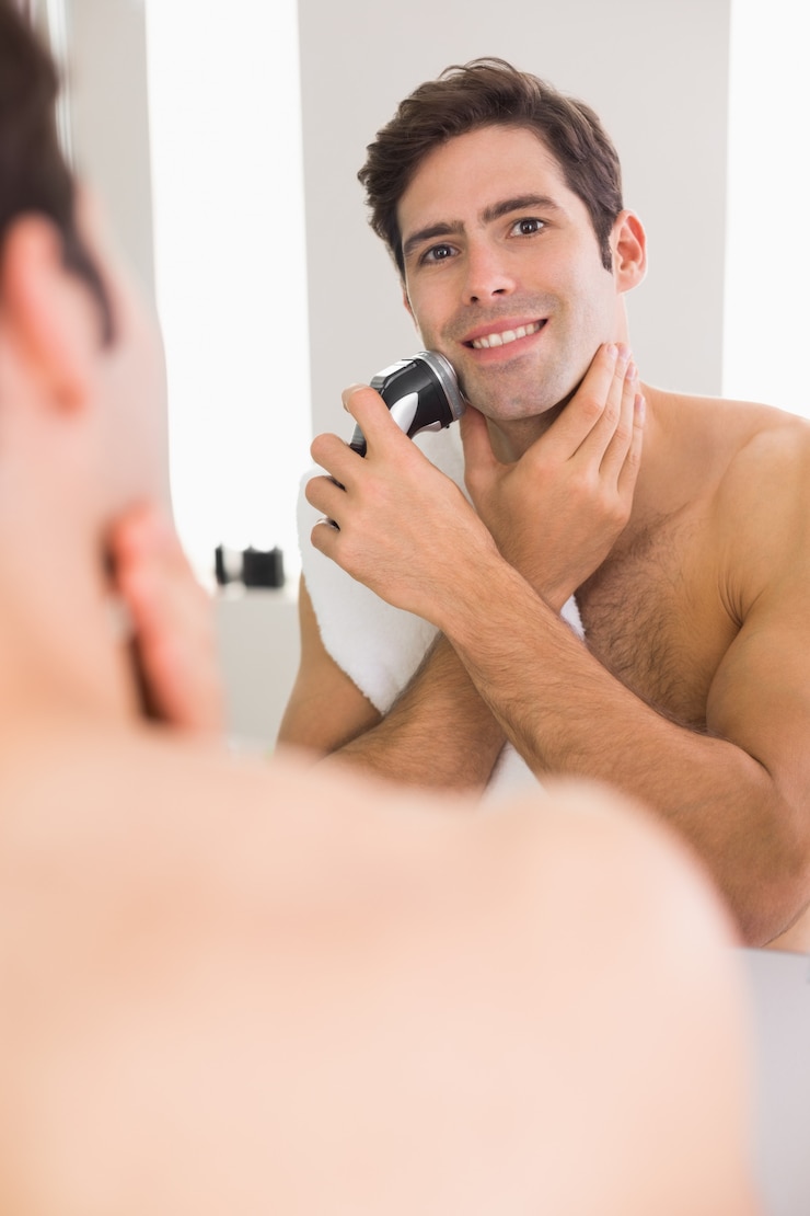Foto reflexo do homem sem camisa, fazer a barba com barbeador elétrico