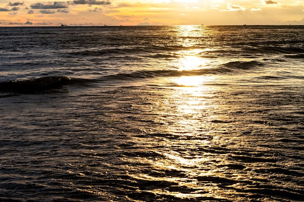 Reflexo dourado da luz do sol no mar à noite